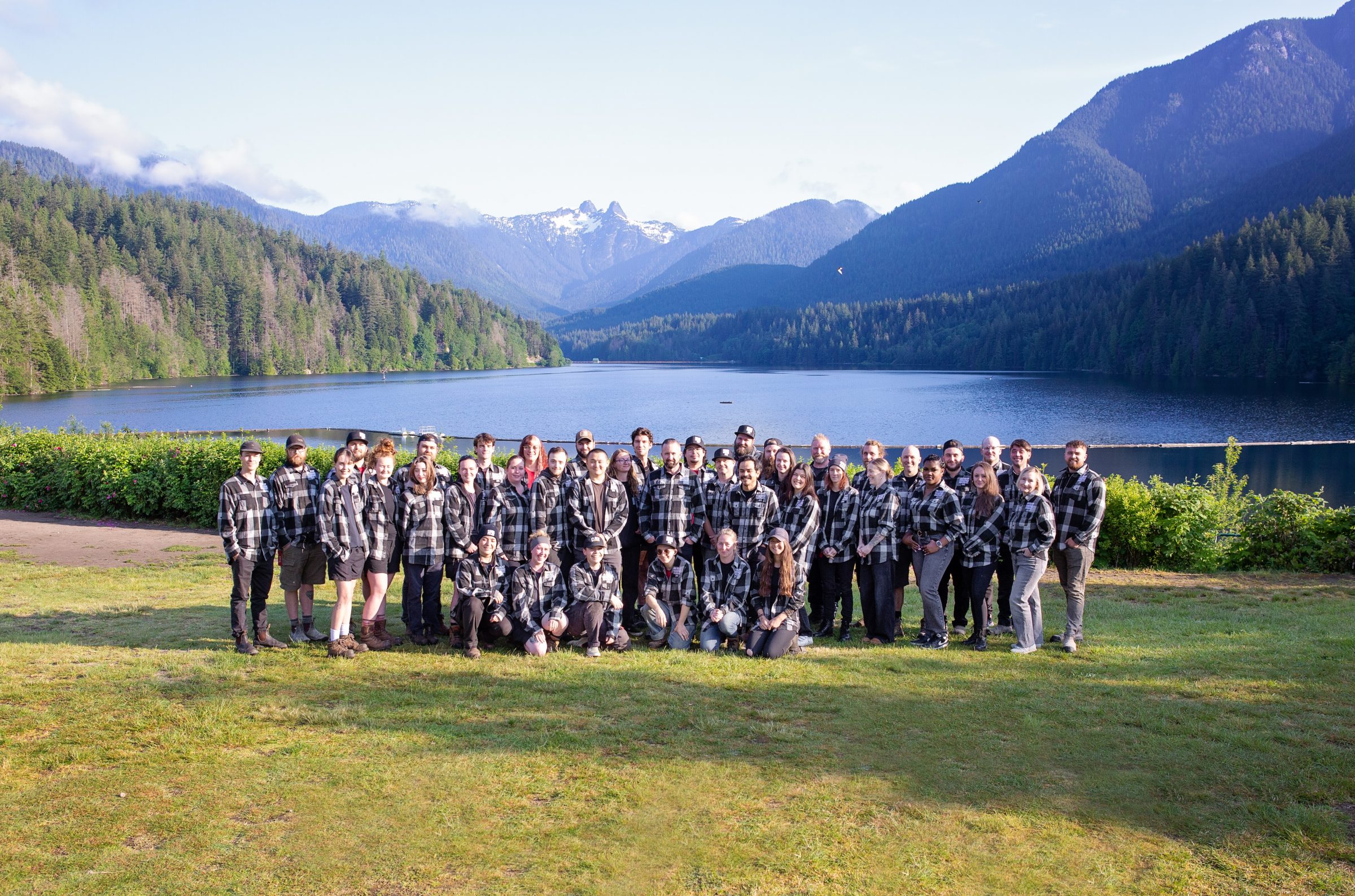 Group in plaid shirts by mountain lake