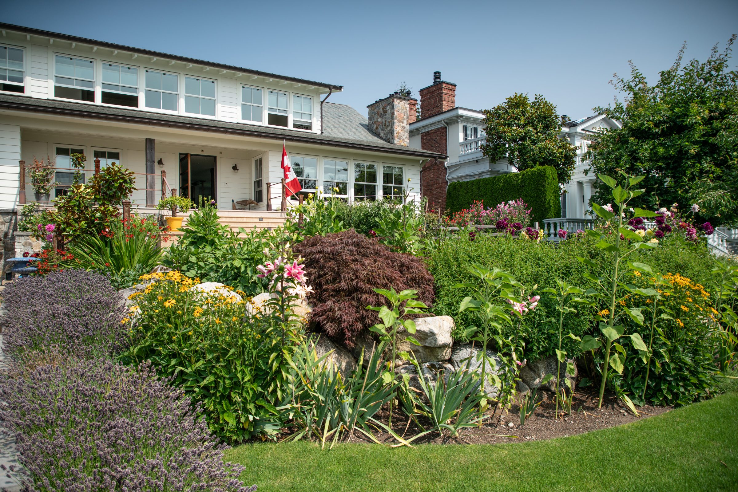 White house with lush garden and Canadian flag