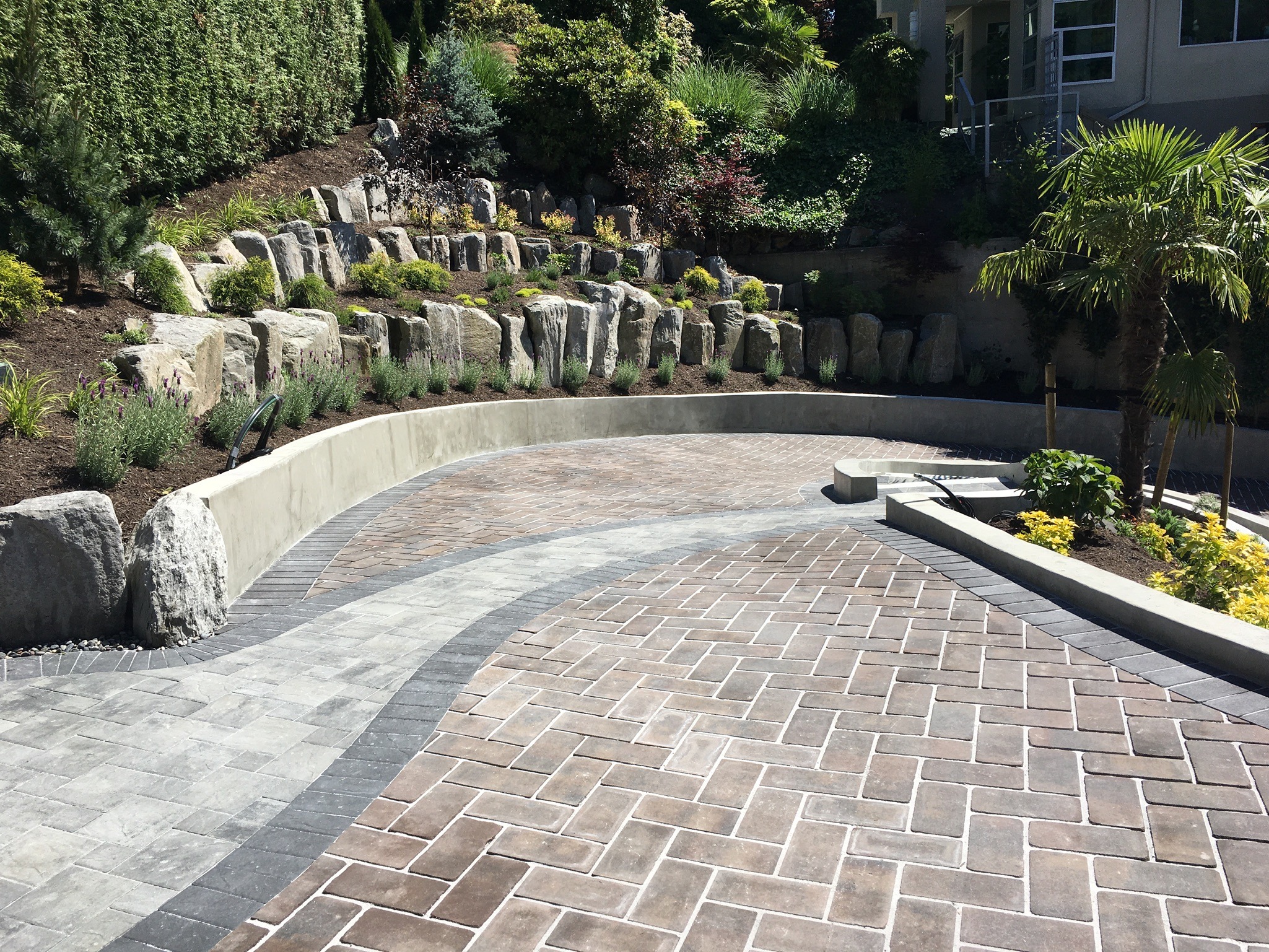 Curved brick patio with stone retaining wall