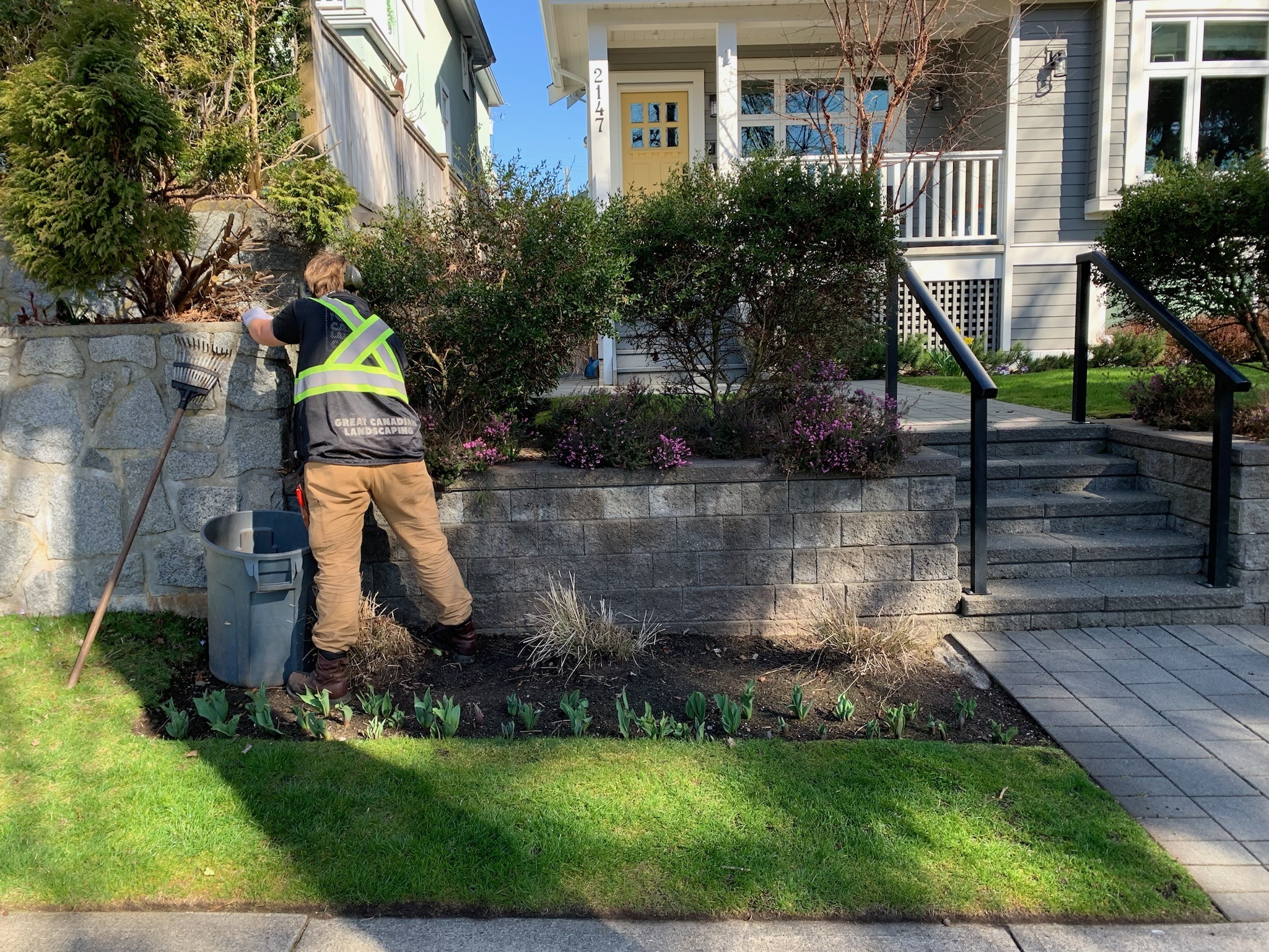 Landscaper tending garden bed by stone wall