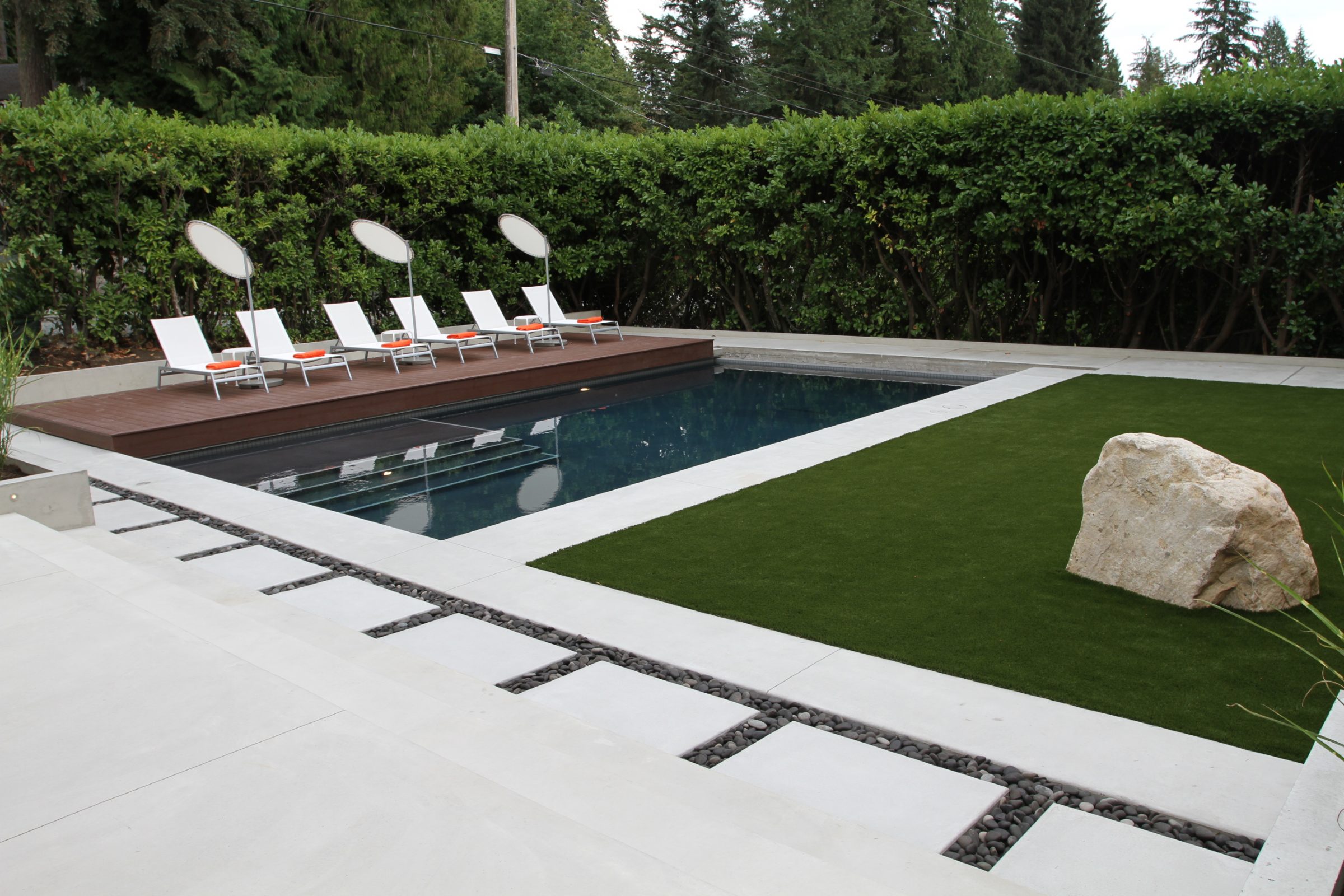 Modern backyard pool with lounge chairs and deck