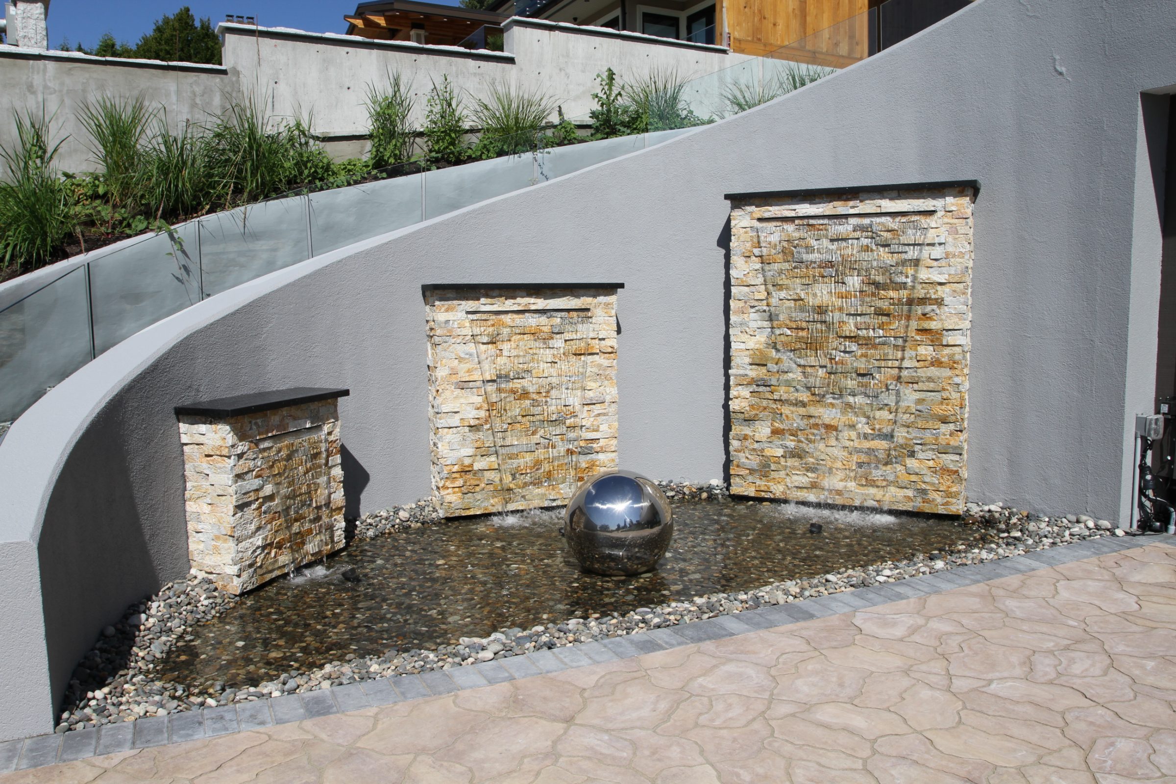 Modern stone wall waterfall with reflective sphere