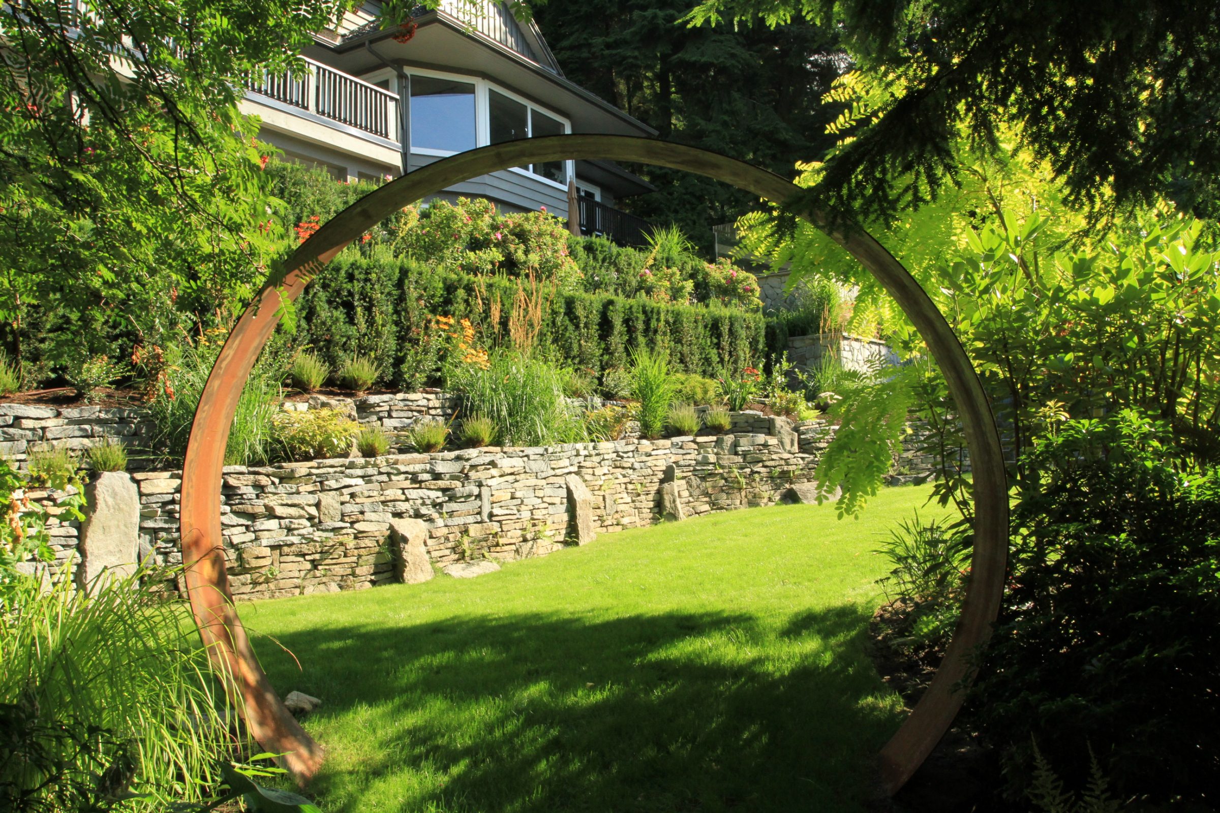 Circular metal sculpture in landscaped terraced garden