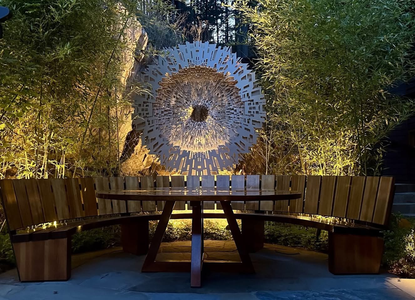 Illuminated outdoor seating with circular bench and wall art