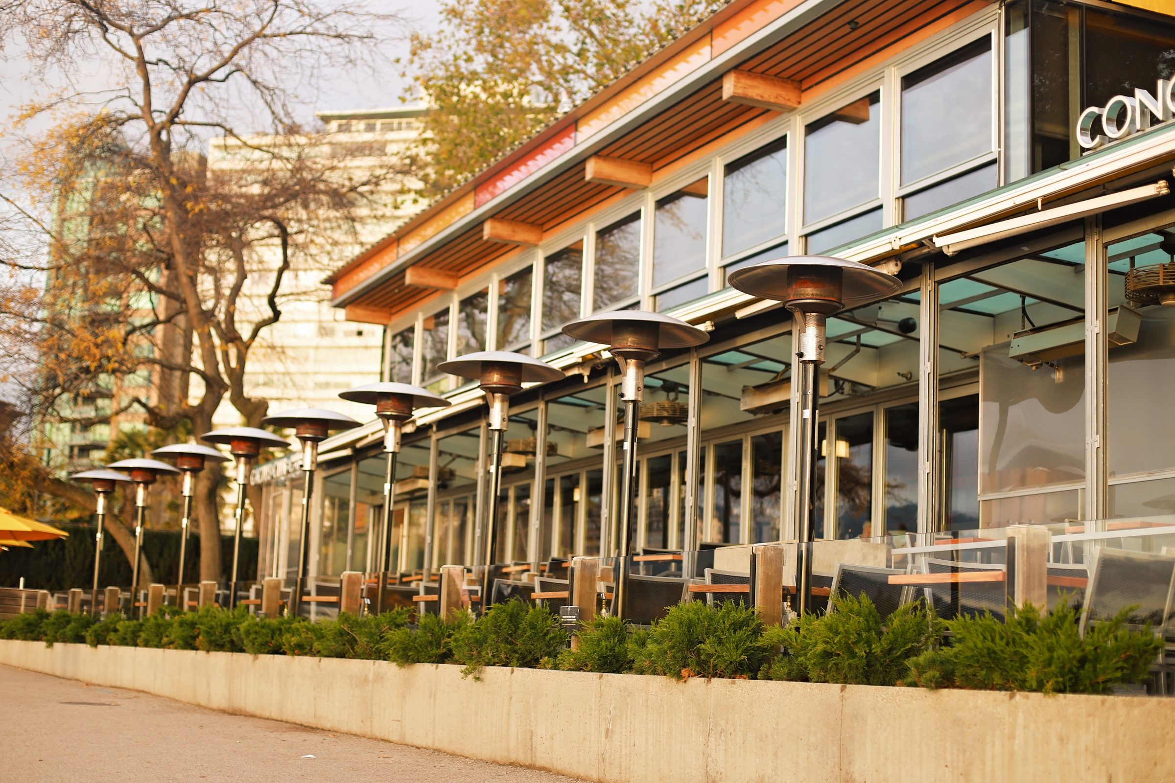 Outdoor restaurant patio with heaters and glass facade