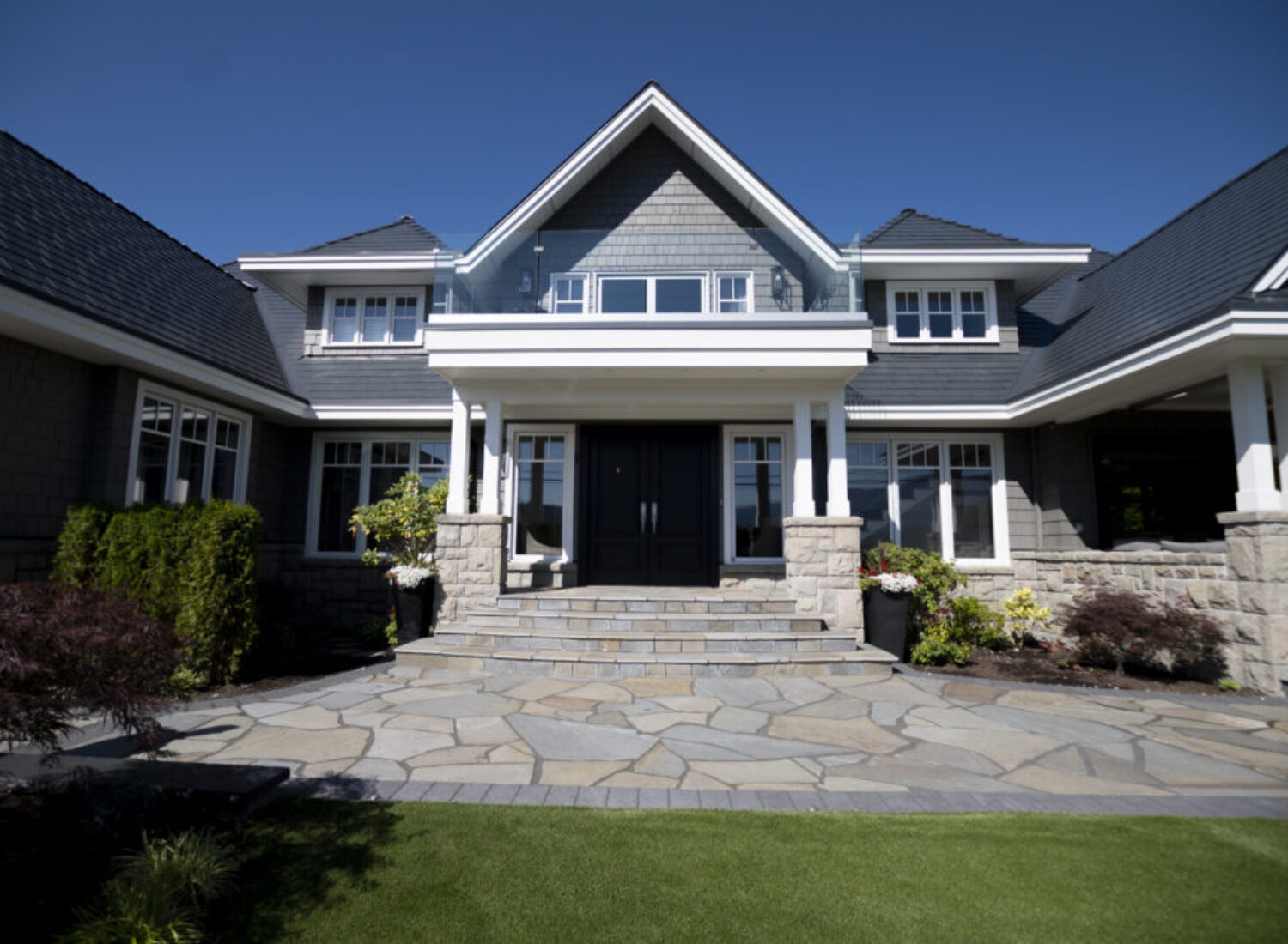 Modern luxury home with stone entryway and lawn