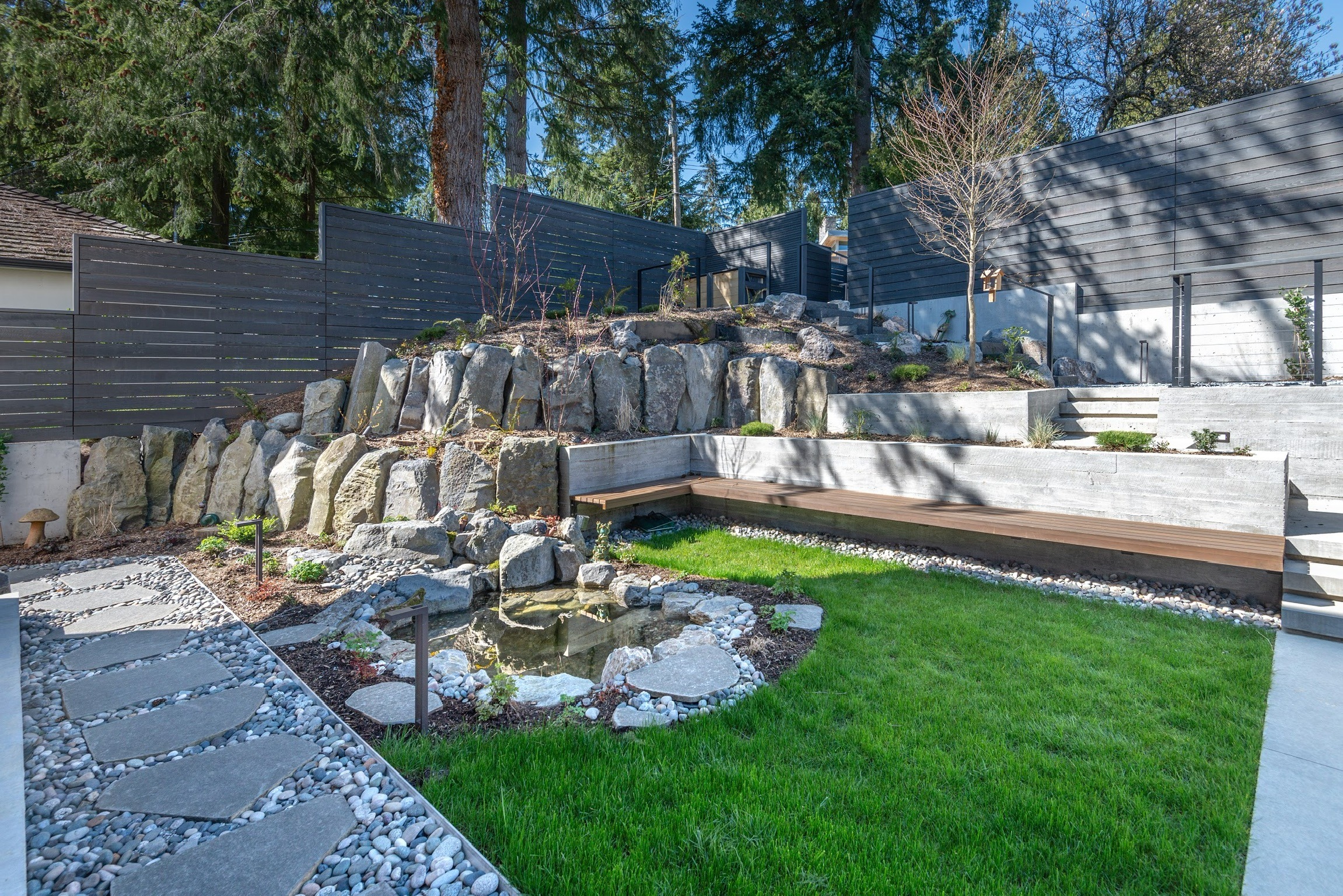 Modern terraced backyard with rock wall and pond
