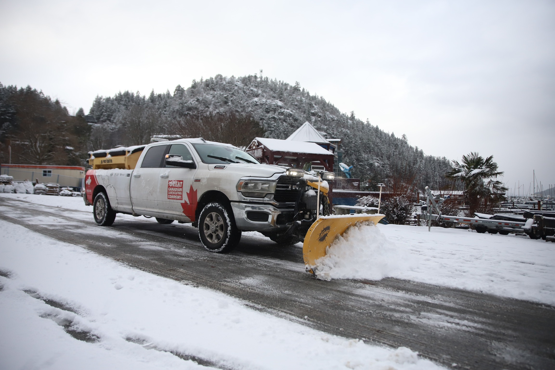 Snowplow truck clearing snowy road near marina