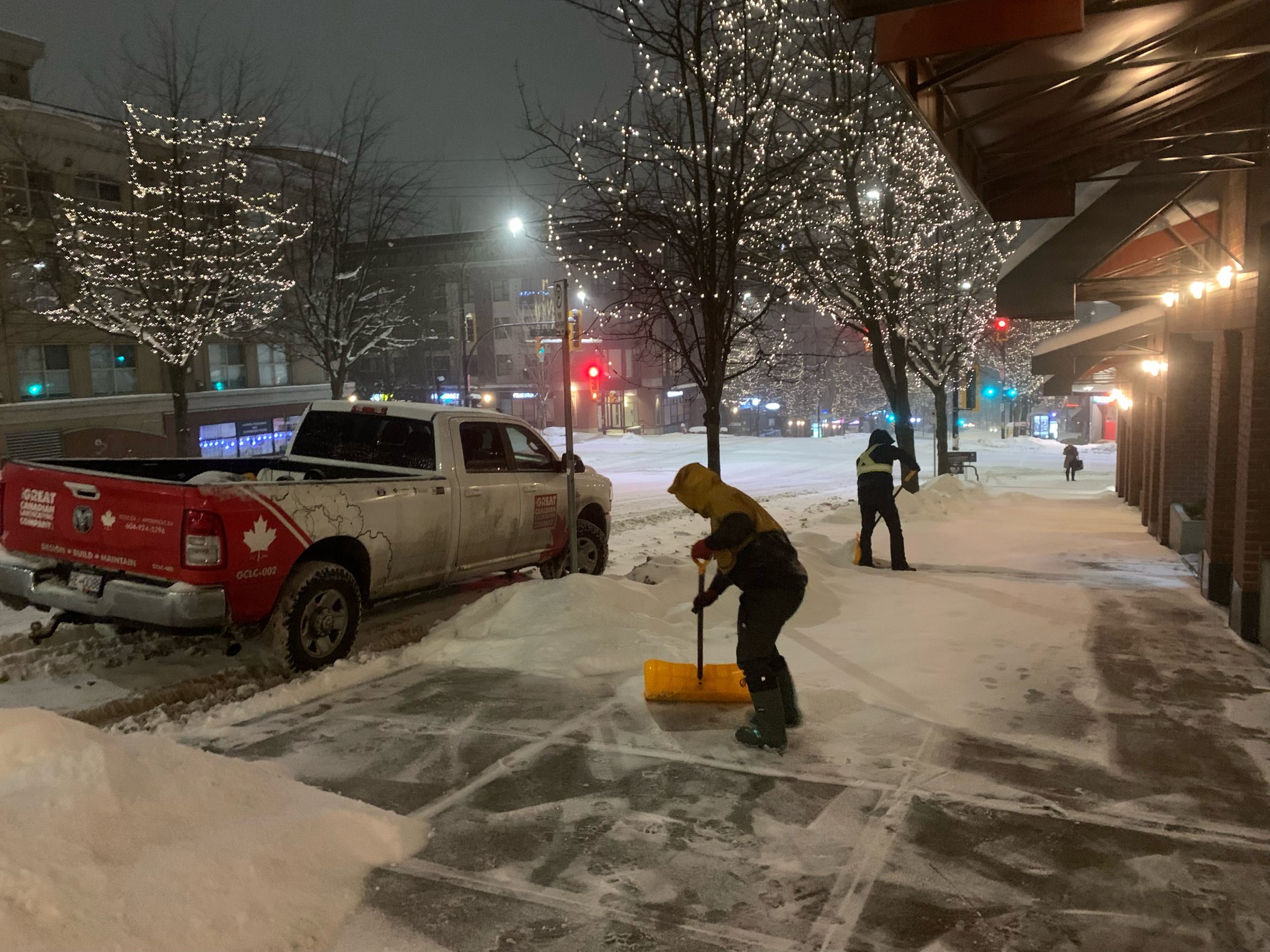 Workers shoveling snow on city sidewalk at night