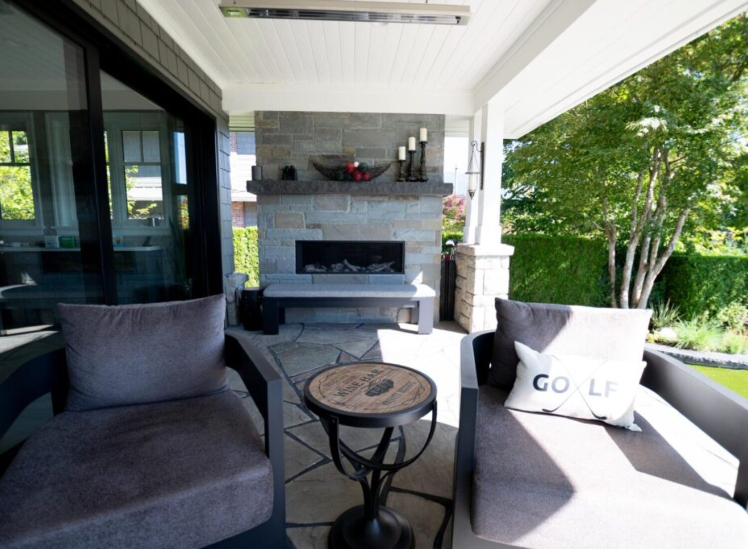 Covered patio with stone fireplace and chairs