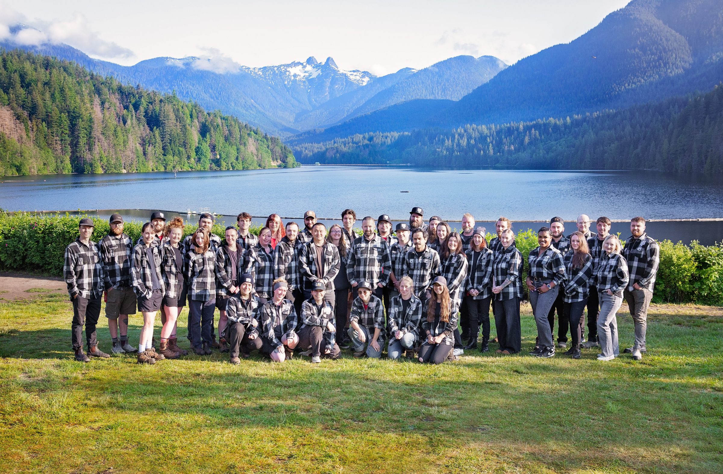 Team posing by mountain lake and forest