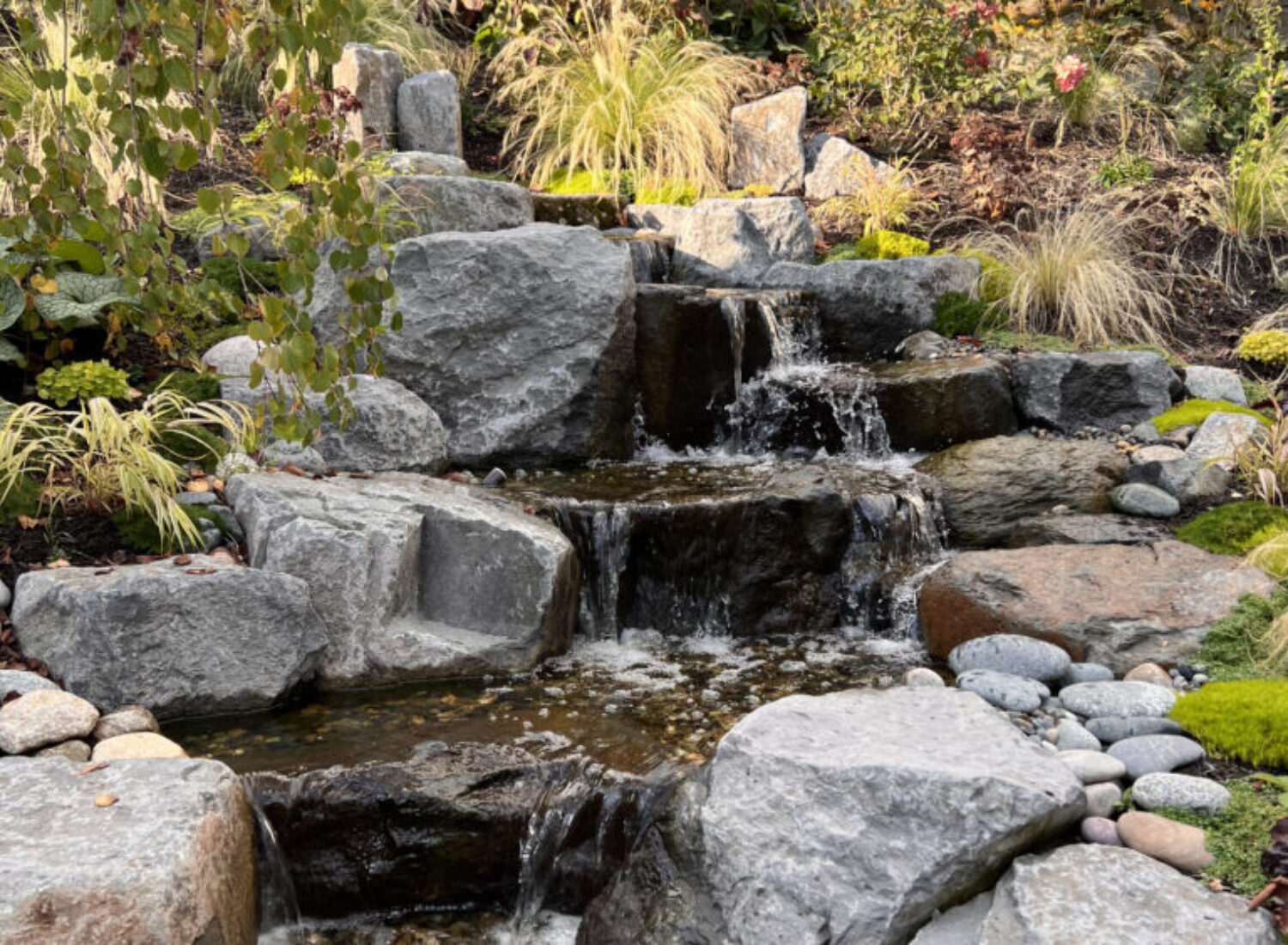 Tiered garden waterfall flowing over large rocks