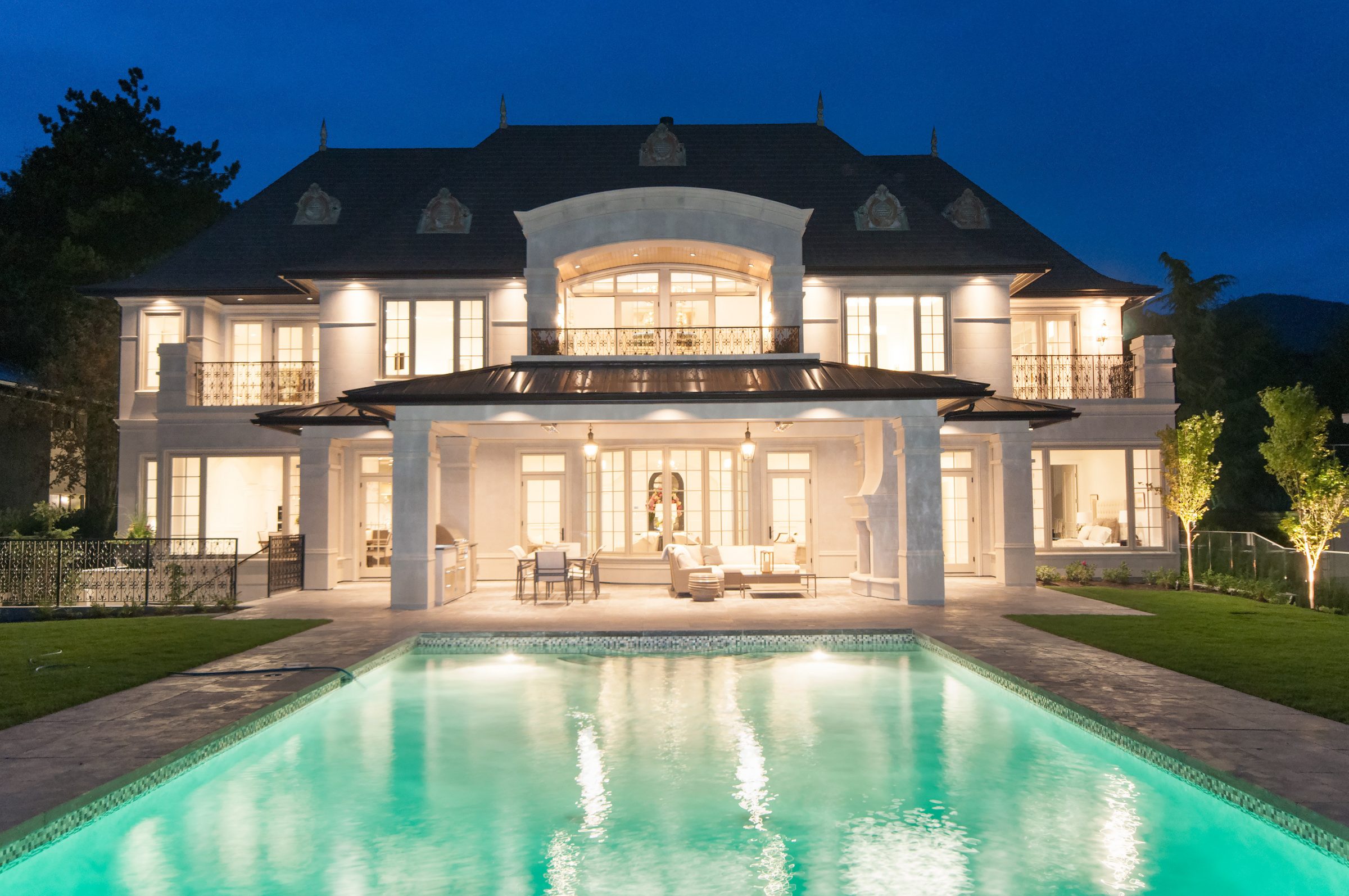 Luxury mansion with illuminated pool at night