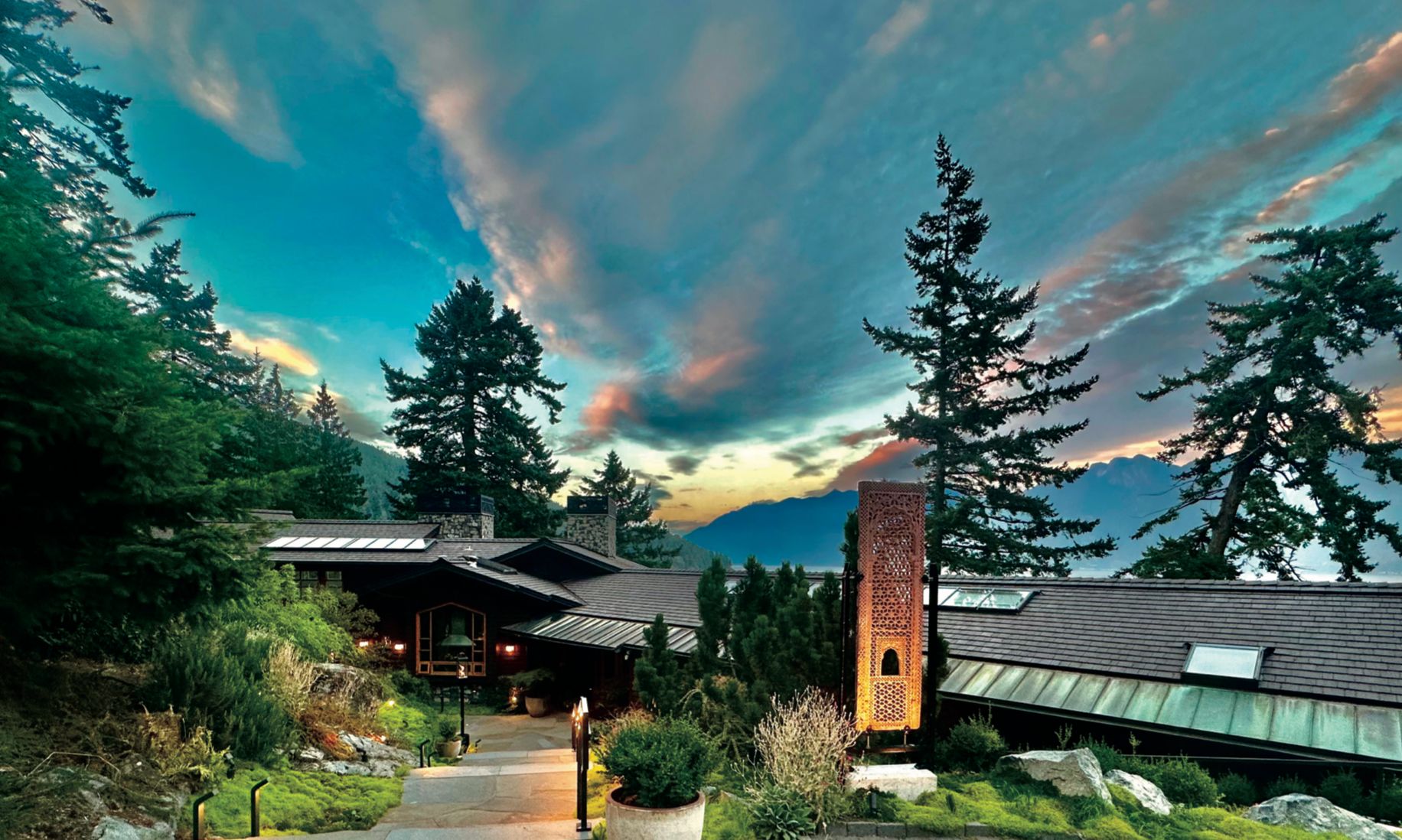 Modern mountain home at sunset among tall trees