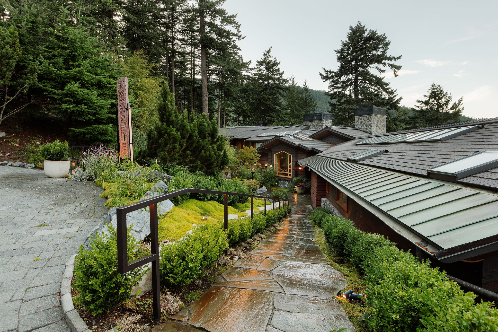 Modern mountain home with stone pathway and forest